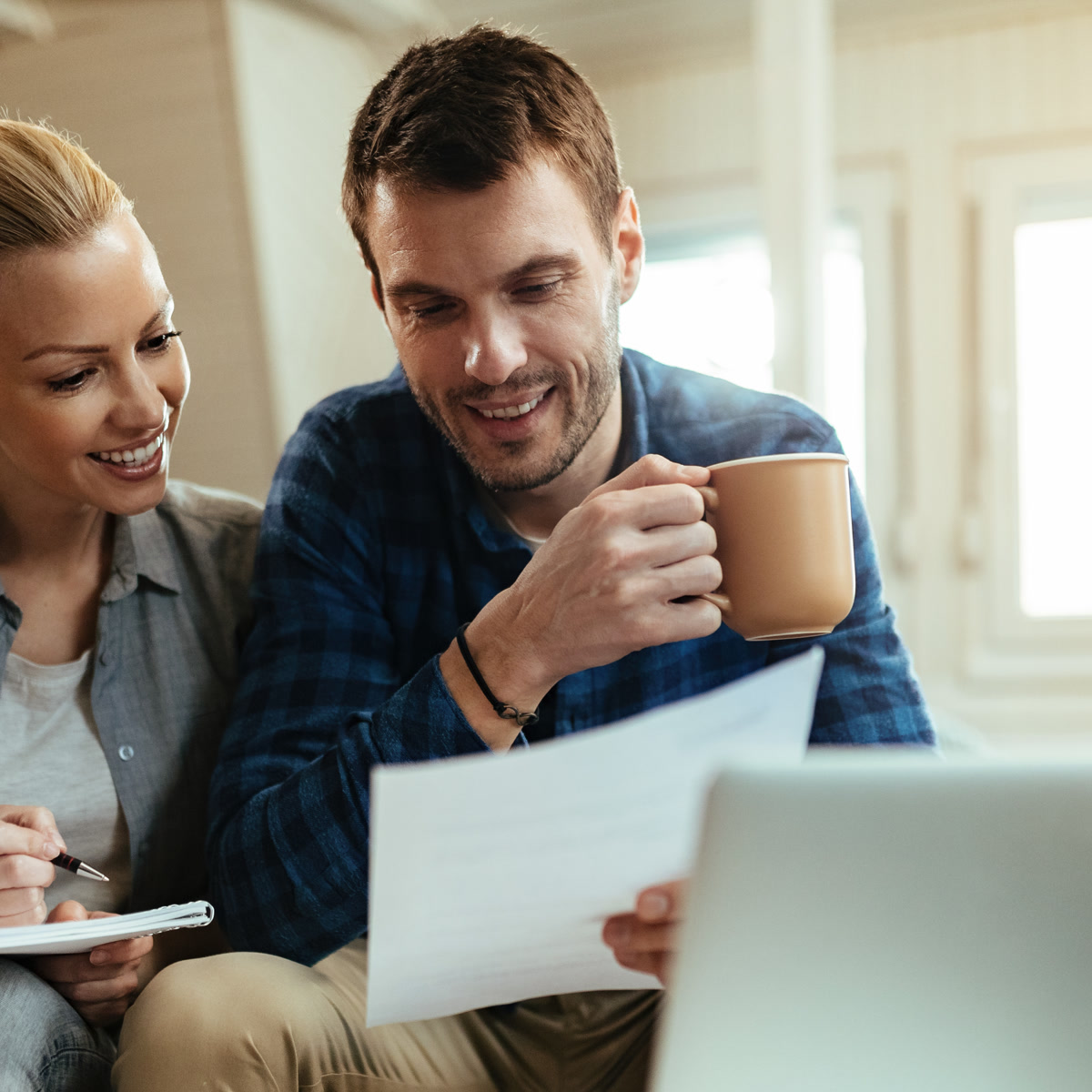 Smiling couple reviewing home finances and property documents together